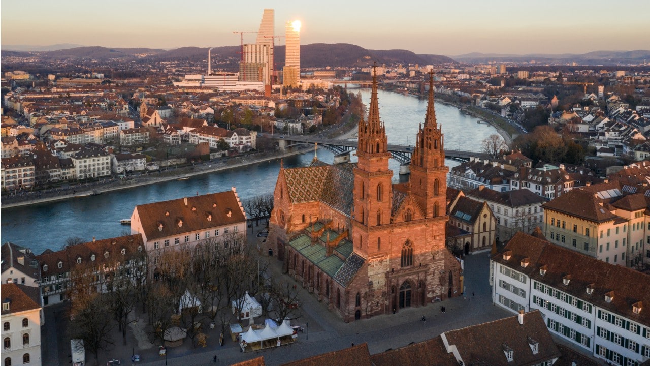 Aerial view of the Basel medieval old town with its cathedral along the Rhine river with modern officel buildings in the background, in Switzerland
