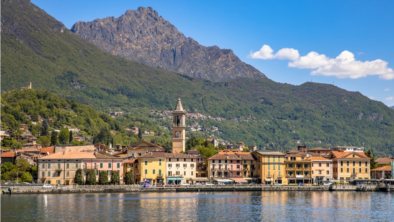 View of city of Porlezza on the shore of lake Lugano With the Alps in the background seen from lake, Cima, Lombardia, Italy